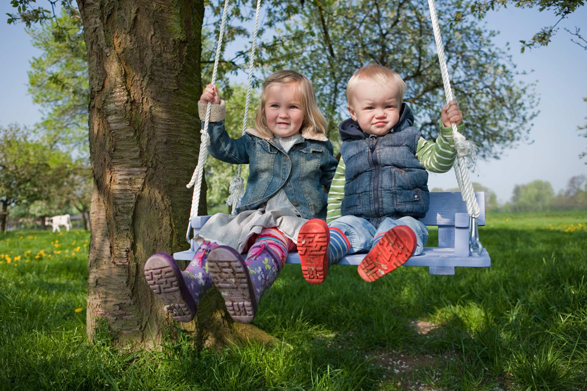 Kinderspielgeräte, wie eine Schaukel für den Garten 2 Kleine Kinder auf einer selbstgebauten Baumschaukel